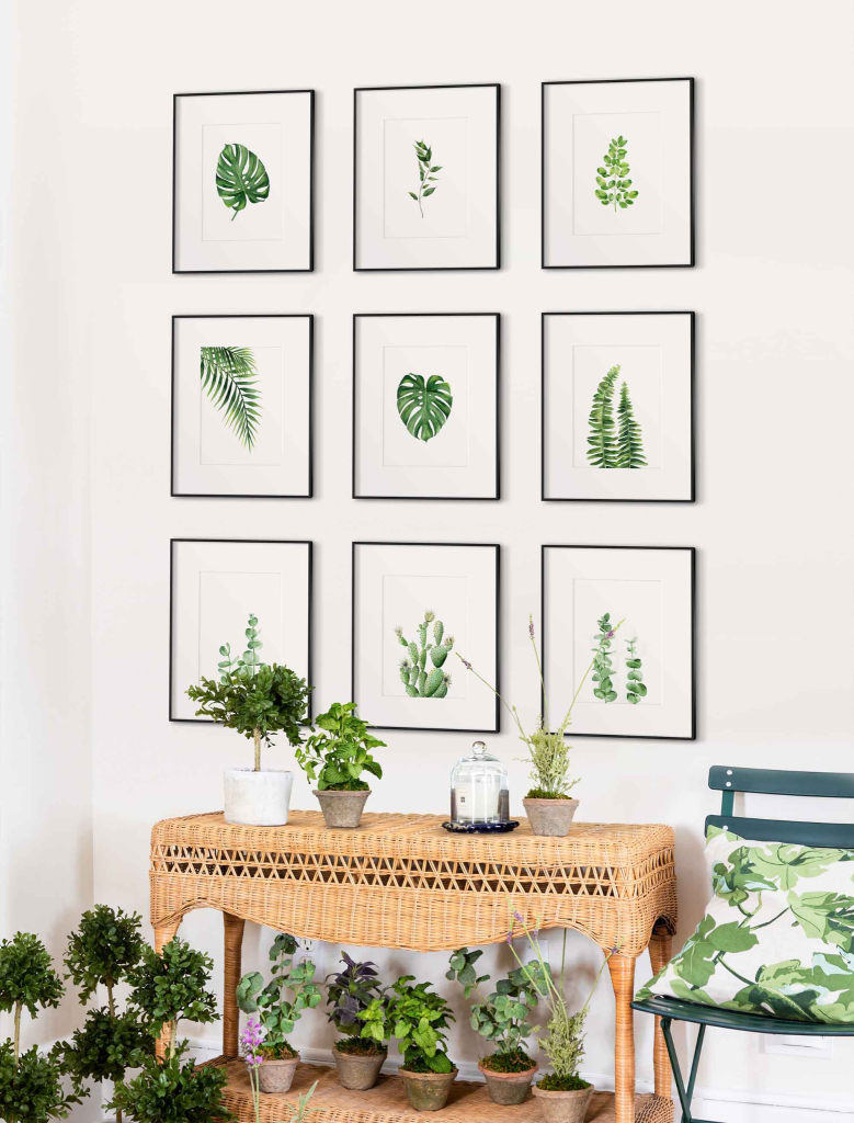 Botanical wall art with green leaf prints arranged in a grid above a rattan table with indoor plants in a modern living room